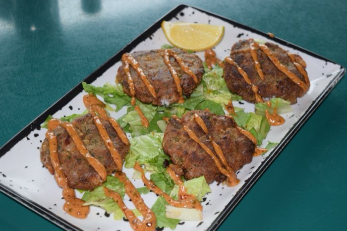 Crispy cakes with sauce over lettuce on a green table